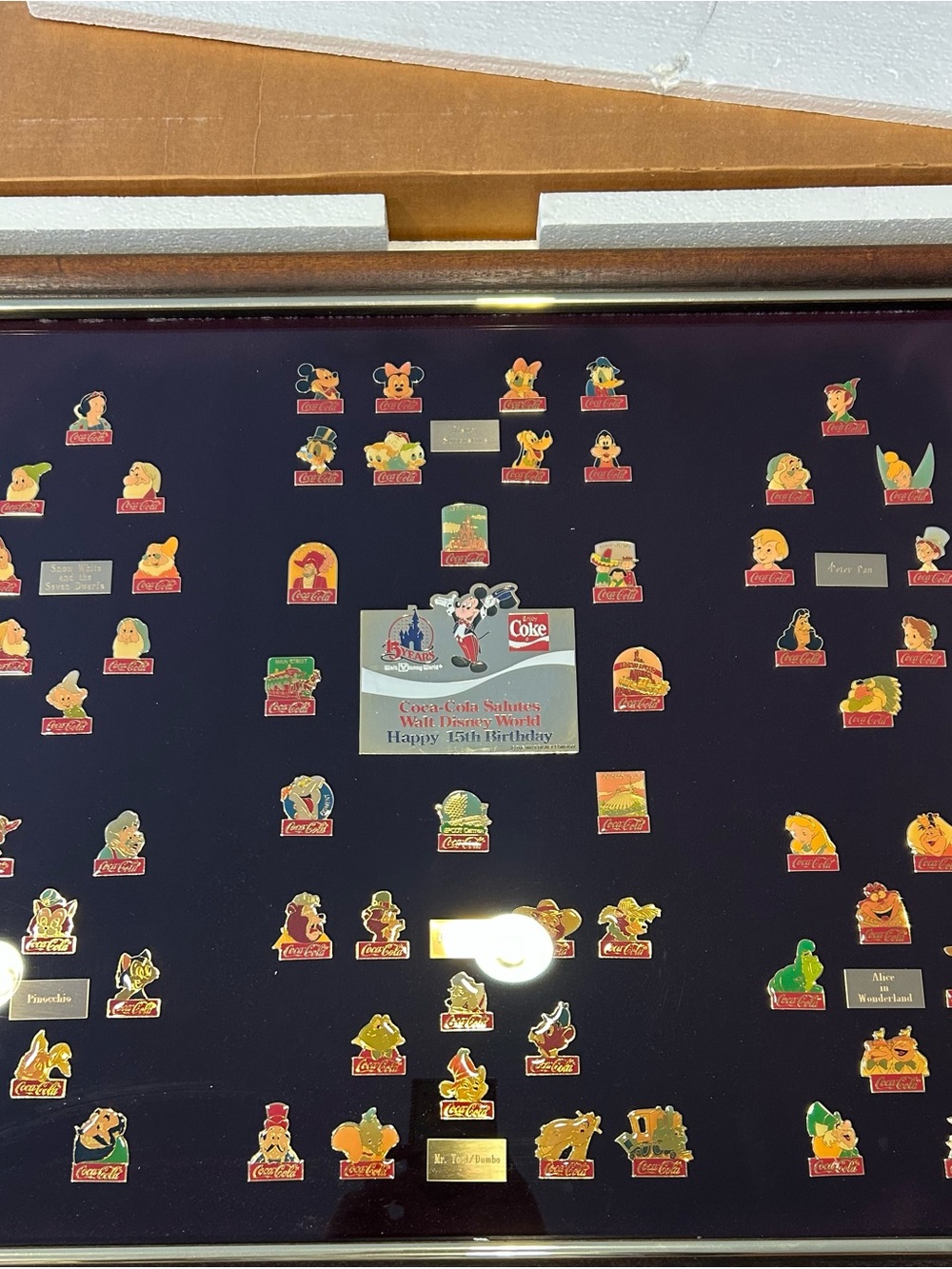 Coca-Cola Disney Character Pin Collection on Dark Blue Mat